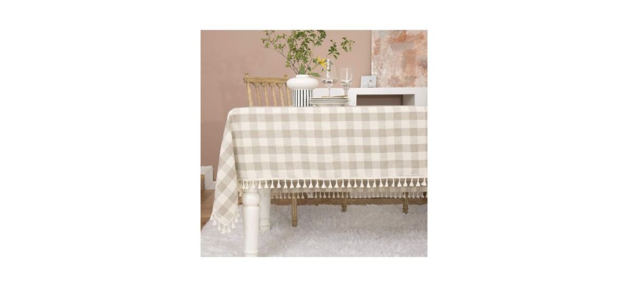 A beige and ivory buffalo plaid tablecloth with tassels at the bottom