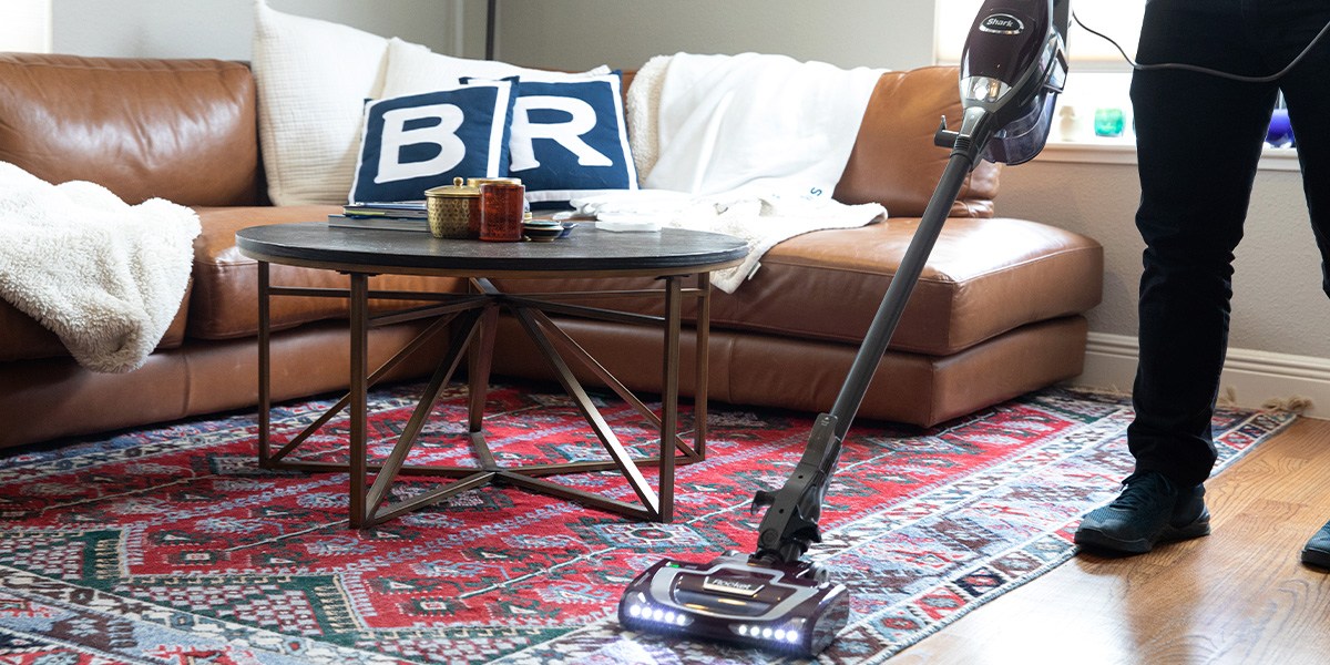 Person using Shark Rocket Deluxe Pro Corded Stick Vacuum on area rug