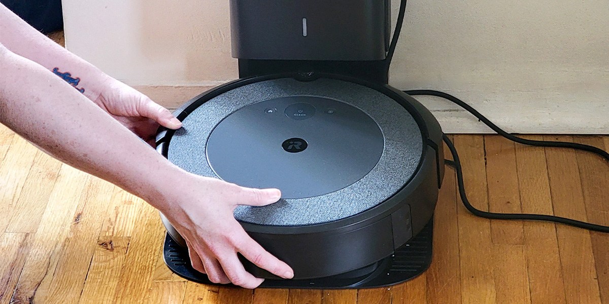 person placing robotic vacuum on charging dock